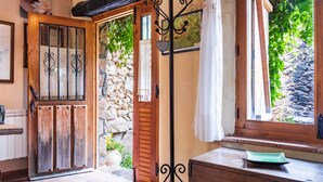 Un interno rustico con una porta in legno, un muro in pietra e una finestra che si affaccia sul verde.