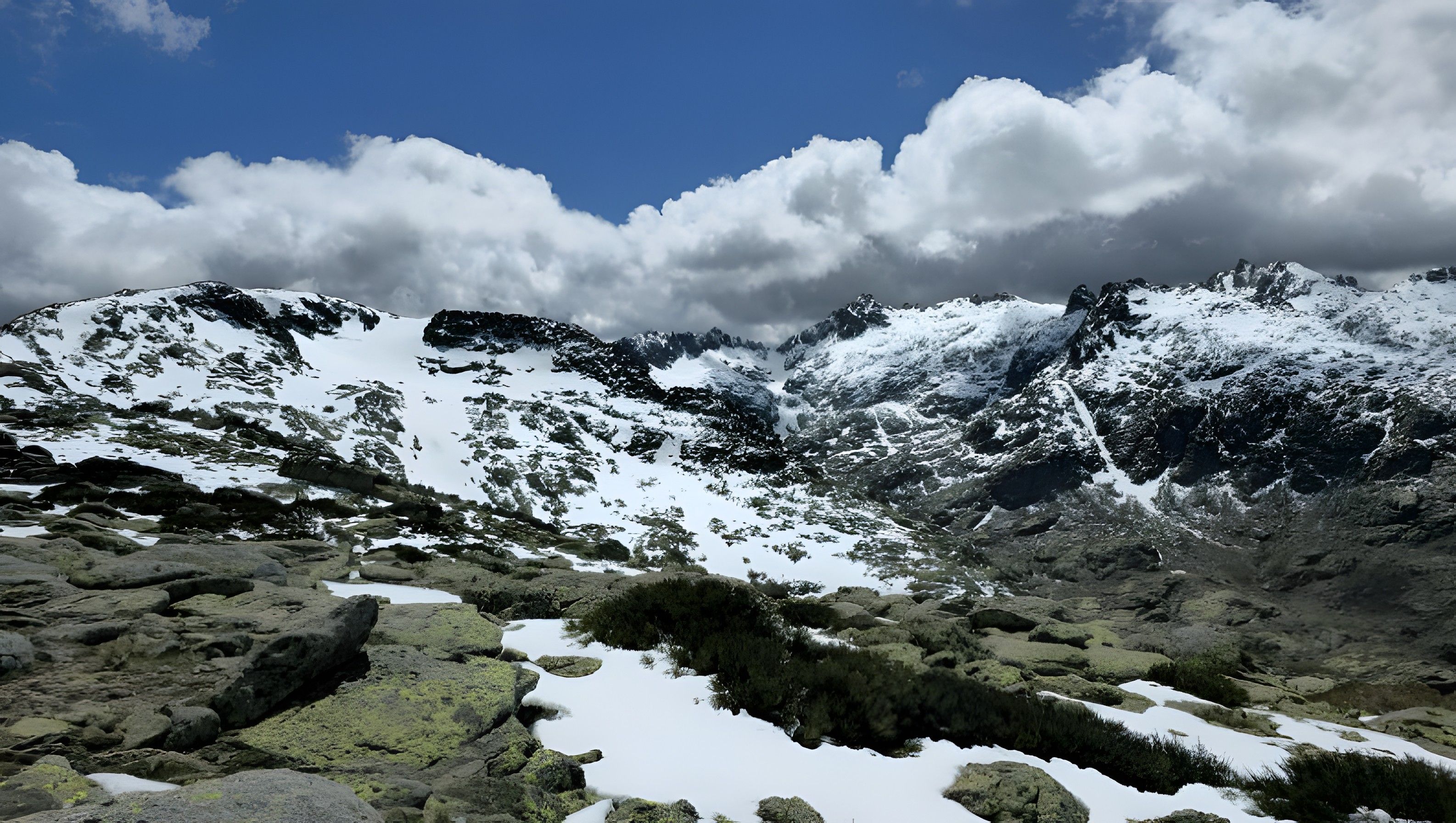 A mountainous landscape with snow-covered peaks and rocky terrain.