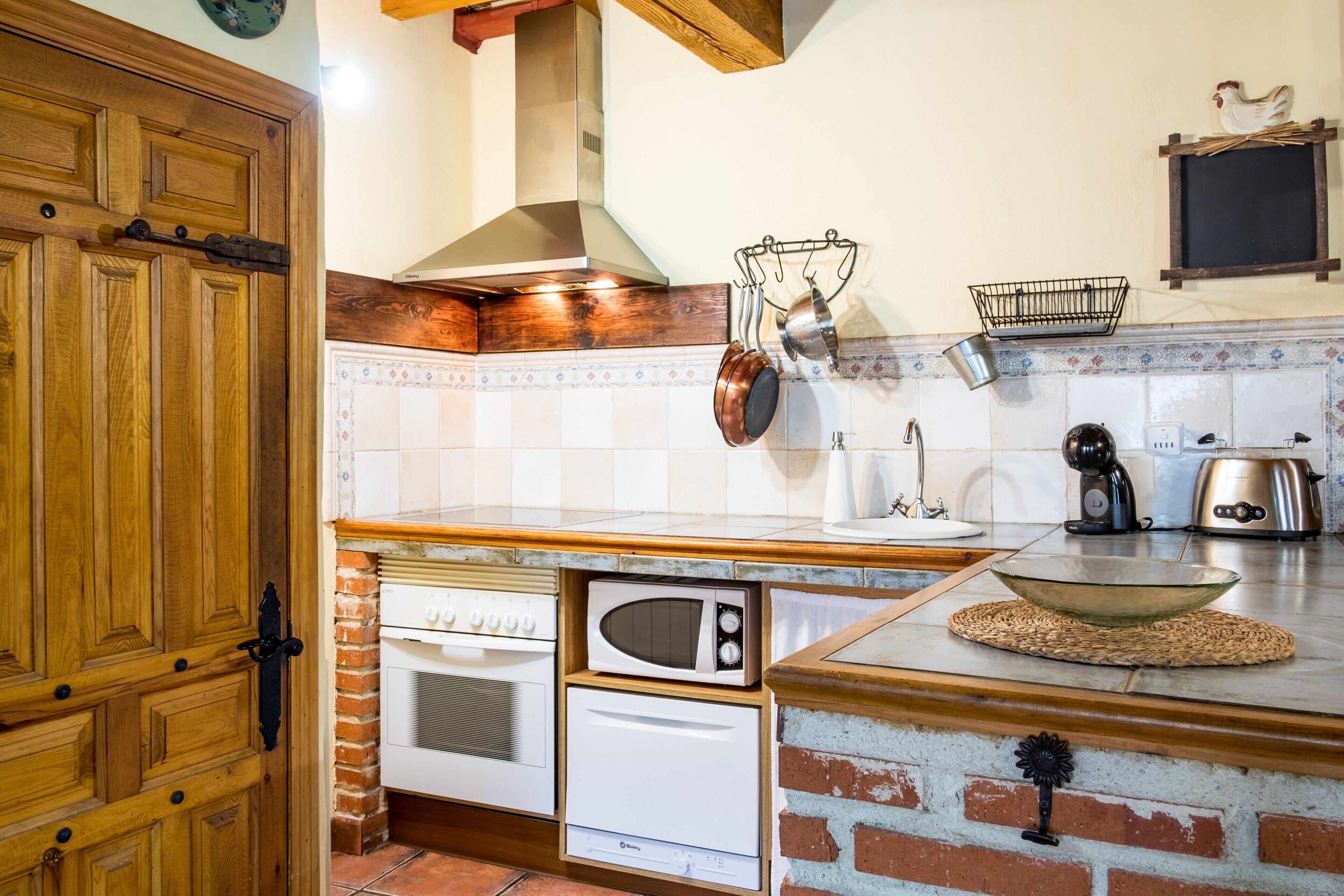 Een keuken met houten kastjes, een magnetron, een broodrooster en een waterkoker.