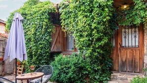 Un patio con tavolo e sedie, una porta in legno e un muro ricoperto d'edera.