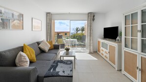 Ein Wohnzimmer mit Sofa, Couchtisch, Fernseher und Balkon mit Aussicht.