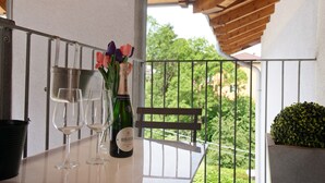 A balcony with a table, two wine glasses, a bottle of champagne, and a vase with flowers. - Apartment 'Residenza La Fonte Second Floor' with Unbeatable Sasso del Ferro View (Laveno-Mombello)