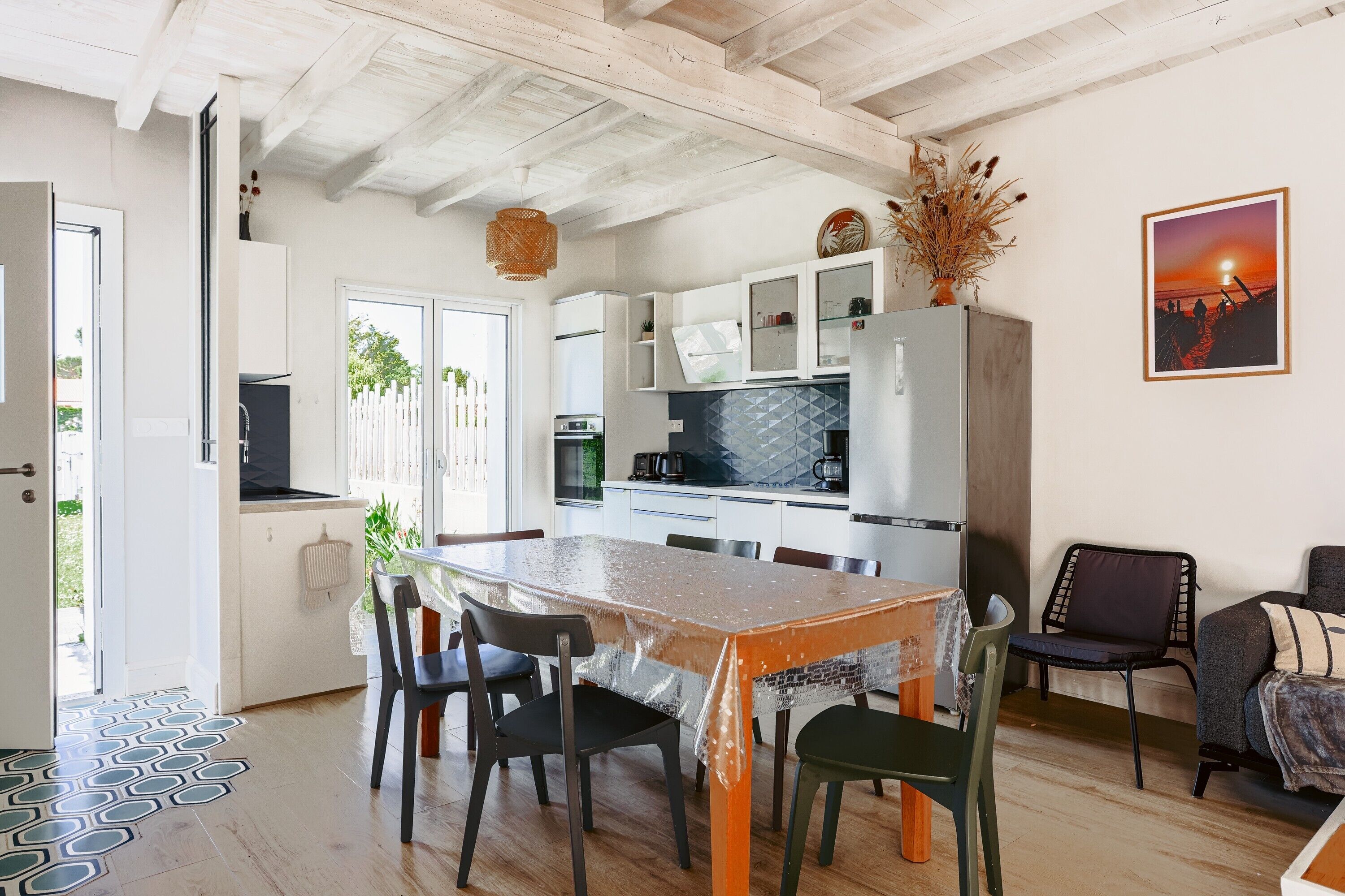 A kitchen with a dining table, chairs, and a refrigerator.