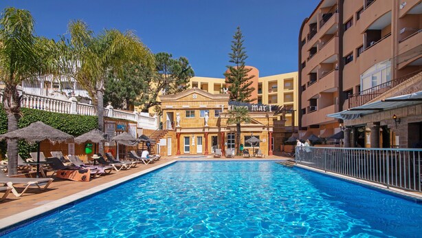 A swimming pool with lounge chairs, a building with a classical facade, and a clear blue sky. - Apartment 'Silva' with Shared Pool, Wi-Fi and Air Conditioning (Albufeira)