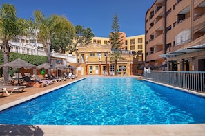A swimming pool with lounge chairs, a building with a classical facade, and a clear blue sky. - Apartment 'Silva' with Shared Pool, Wi-Fi and Air Conditioning (Albufeira)