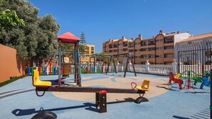 A playground with swings, a slide, and a climbing structure. - Apartment 'Silva' with Shared Pool, Wi-Fi and Air Conditioning (Albufeira)