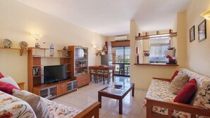 A living room with a television, sofa, coffee table, and dining area. - Apartment 'Silva' with Shared Pool, Wi-Fi and Air Conditioning (Albufeira)