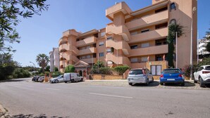 A multi-story building with balconies, parked cars, and a clear sky. - Apartment 'Silva' with Shared Pool, Wi-Fi and Air Conditioning (Albufeira)