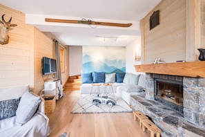 A cozy living room with a fireplace, wooden walls, a sofa, and a television.