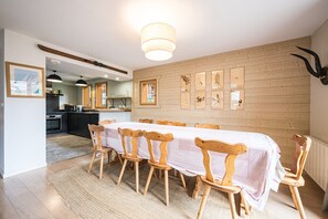Un comedor con una larga mesa, sillas de madera y un ciervo montado en la pared.