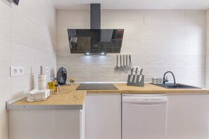 Una cocina moderna con armarios blancos, una campana extractora negra y un lavavajillas.