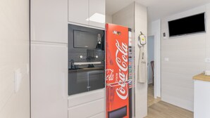 A modern kitchen with a microwave, oven, and a refrigerator with a Coca-Cola design. - Coastal Charm – Vacation Apartment in Ayamonte (Ayamonte)