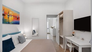 Habitación de hotel moderna con cama, escritorio, televisor y un cuadro en la pared.