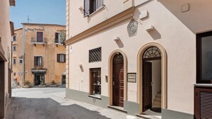 Una calle estrecha con edificios que tienen puertas abovedadas y un letrero de un negocio.