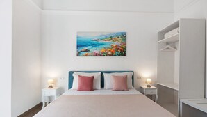 Un dormitorio con una cama, dos mesitas de noche, un cuadro y un armario.