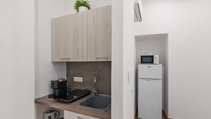Una cocina compacta con microondas integrado, cafetera y lavabo.