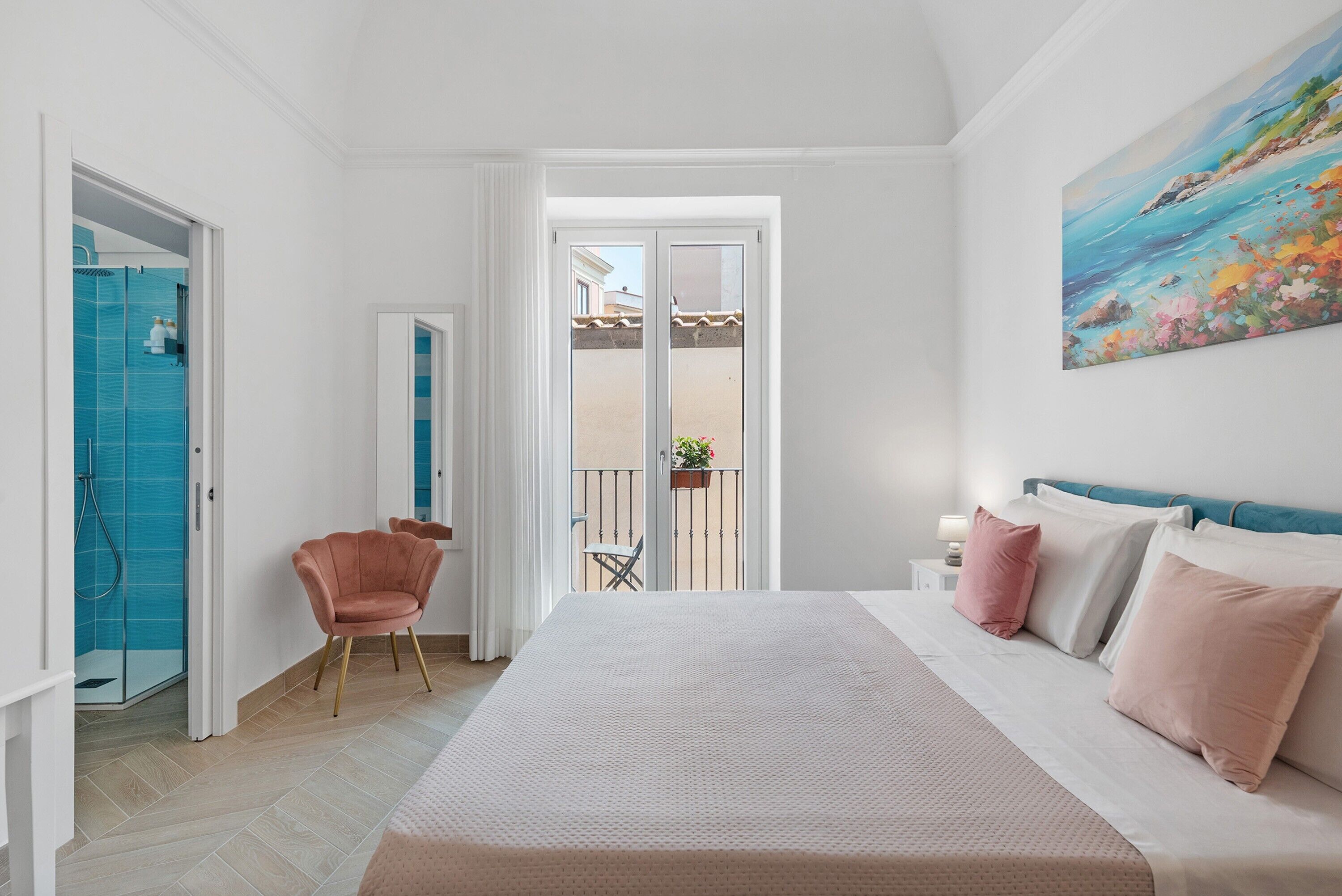 Une chambre à coucher avec un lit, une chaise, un balcon avec vue et un tableau au mur.