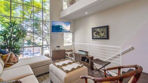 Un salón espacioso con un ventanal grande, una televisión y vistas al exterior.