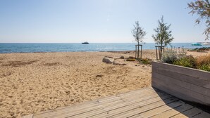 A beach with a wooden deck, a clear sky, and a distant ship. - Les Boucaniers by Interhome (Sainte Maxime)