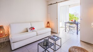 A modern living room with a white sofa, two black coffee tables, and a view of an outdoor dining area. - Les Boucaniers by Interhome (Sainte Maxime)