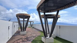 A rooftop terrace with a pathway, metal structures, and a view of the ocean.