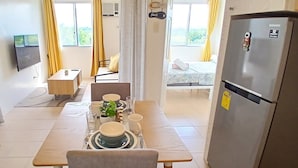 A compact kitchen with a dining area, a refrigerator, and a television.