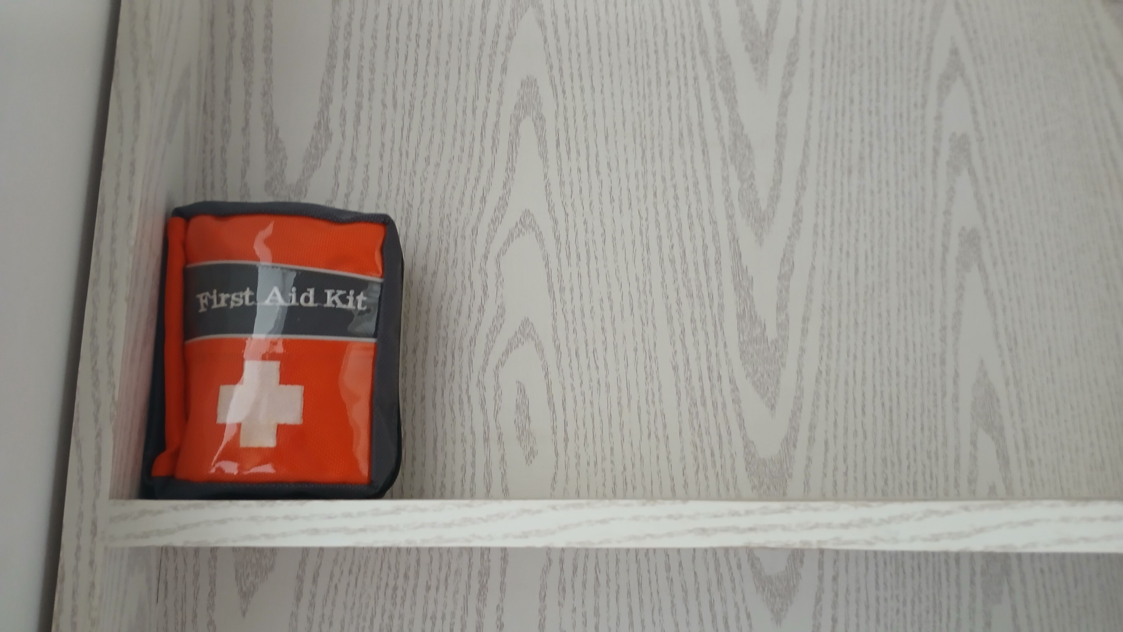 Une trousse de premiers secours sur une surface en bois blanche.