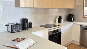 A modern kitchen with a toaster, coffee maker, and a black electric kettle on the counter. - Wangi Waterfront Escape, Walk to Cafes, Parks & Lake Reserve (Wangi Wangi)
