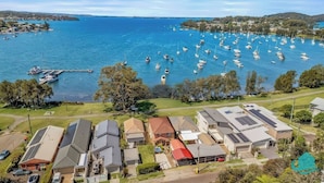 A coastal residential area with houses, a marina with boats, and a clear view of the sea. - Wangi Waterfront Escape, Walk to Cafes, Parks & Lake Reserve (Wangi Wangi)