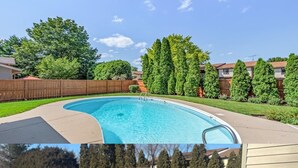 A swimming pool with a curved edge, surrounded by a wooden fence and trees. - In-Ground Pool AND Hot Tub! Fenced Yard, Pet Friendly Home. Near Town! (Crystal Lake)