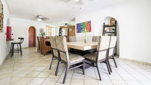 Un coin repas avec une table ronde, six chaises et un ventilateur de plafond.