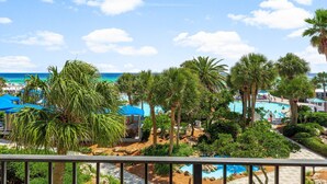 Un resort con piscina rodeada de palmeras y vista al océano.