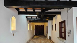 A hallway with patterned tile flooring, a wooden ceiling structure, and a door at the end. - Cozy Colonial Style Azotea Apartments (Jocotenango)