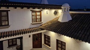 A traditional building with a tiled roof, a bell tower, and a small dome. - Cozy Colonial Style Azotea Apartments (Jocotenango)