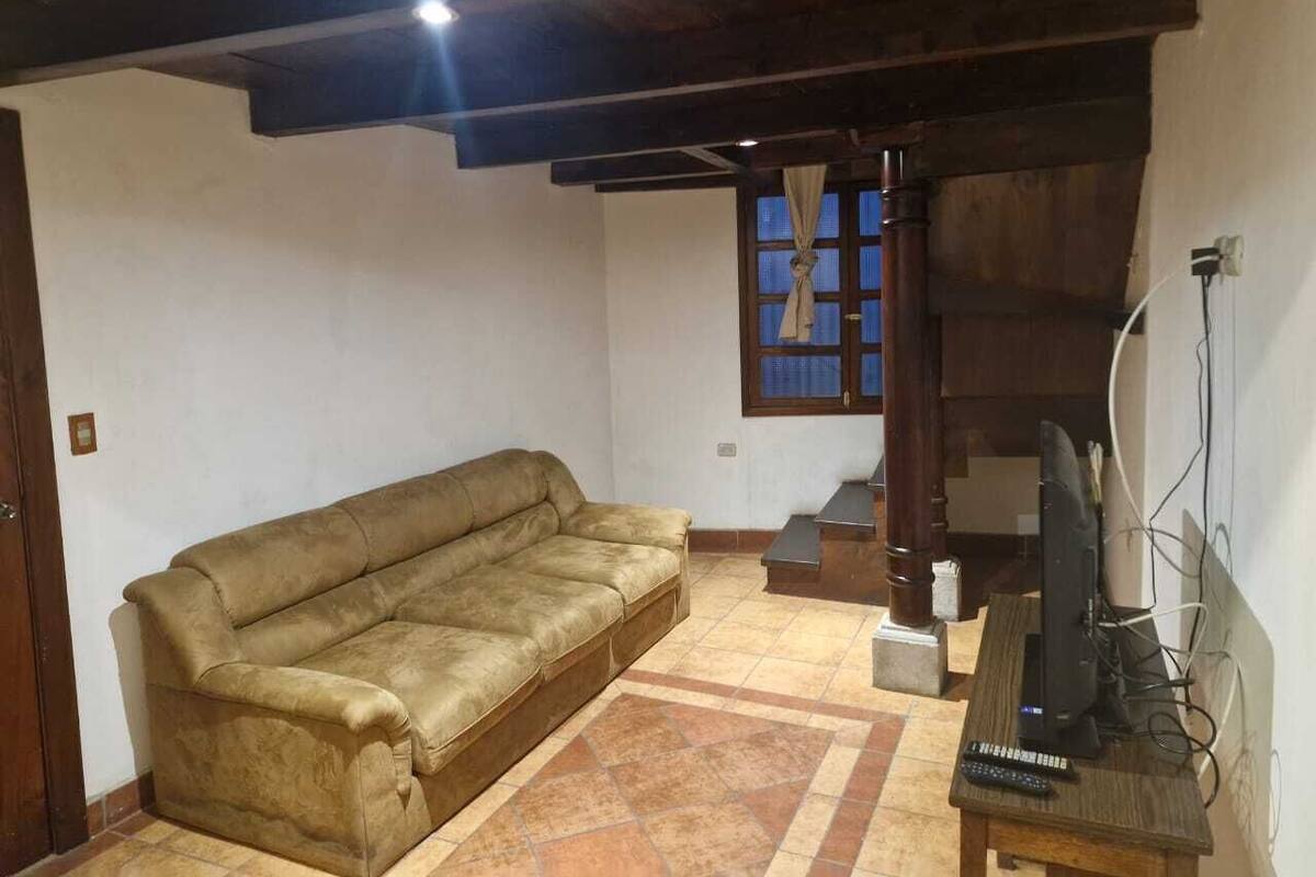 A living room with a sofa, a television, and a staircase.