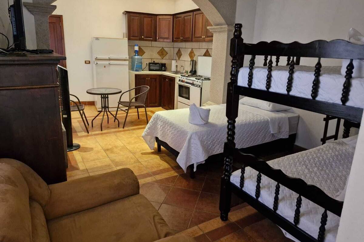 A compact room with a bed, a small table, and a kitchenette.