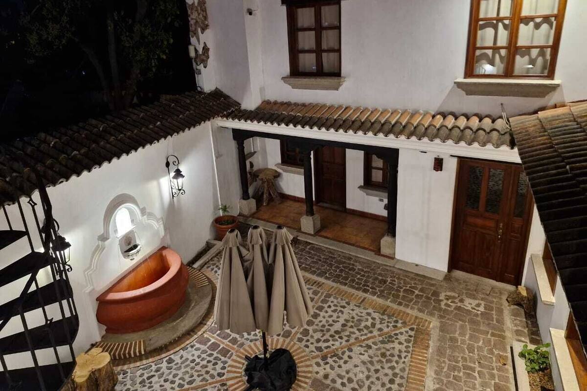 A courtyard with a traditional tiled roof, a large terracotta pot, and a covered seating area with umbrellas.