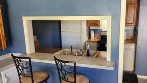 A kitchen with a built-in counter, two chairs, a sink, and cabinets. - Charming 2-bedroom home with fenced yard sleeps 6 in Baton Rouge near Tigerland (Baton Rouge)