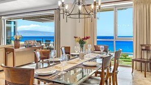 Un espace repas avec une table en verre, des chaises et une vue sur l’océan.
