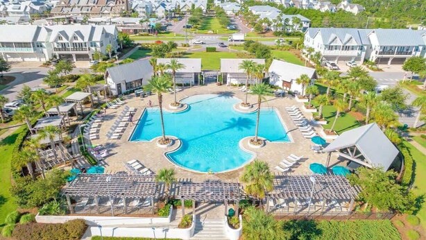 A resort with a central swimming pool, lounge areas, and a view of the ocean.