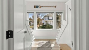 A staircase leading to a landing with a view of a house through a window. - Beach, Breeze & Bunk Beds. FamilyFun Steps to the Shore. Dog-Friendly, GameWall. (Wareham)