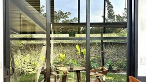 A modern interior with a sliding glass door leading to an outdoor patio area. - NATURAVE HOME - Tiny house with mountain view (Monteverde)