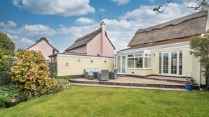 A house with a thatched roof, a conservatory, and a well-maintained garden. - Bosuns Cottage | Dog Friendly Coastal Cottage, 5 Minutes from the Beach (Winterton-on-sea)