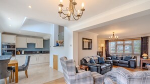 A spacious living room with a sofa set, a dining area with a table and chairs, a kitchen with white cabinets, and a chandelier. - Bosuns Cottage | Dog Friendly Coastal Cottage, 5 Minutes from the Beach (Winterton-on-sea)