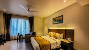 Ein Hotelzimmer mit Bett, Schreibtisch, Stuhl, Deckenventilator und einem Bild an der Wand.
