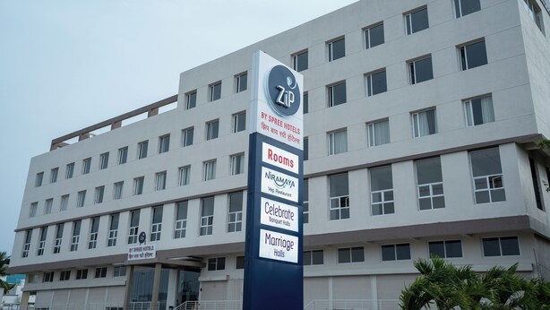 Un edificio de hotel con varios pisos, un letrero que indica que pertenece a Spree Hotels, y diversas comodidades como habitaciones, un restaurante vegetariano, salones de banquetes y salones de bodas.