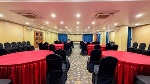 Un salón de conferencias con varias mesas, sillas y piso alfombrado.