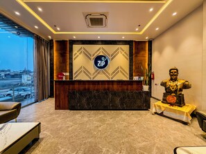 A reception desk with a 'Zipl' sign, a statue, and a view of the outside. - ZiP By Spree Hotels Pandharpur (Pandharpur)