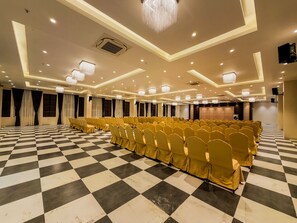 A large hall with rows of chairs, a checkered floor, and chandeliers. - ZiP By Spree Hotels Pandharpur (Pandharpur)