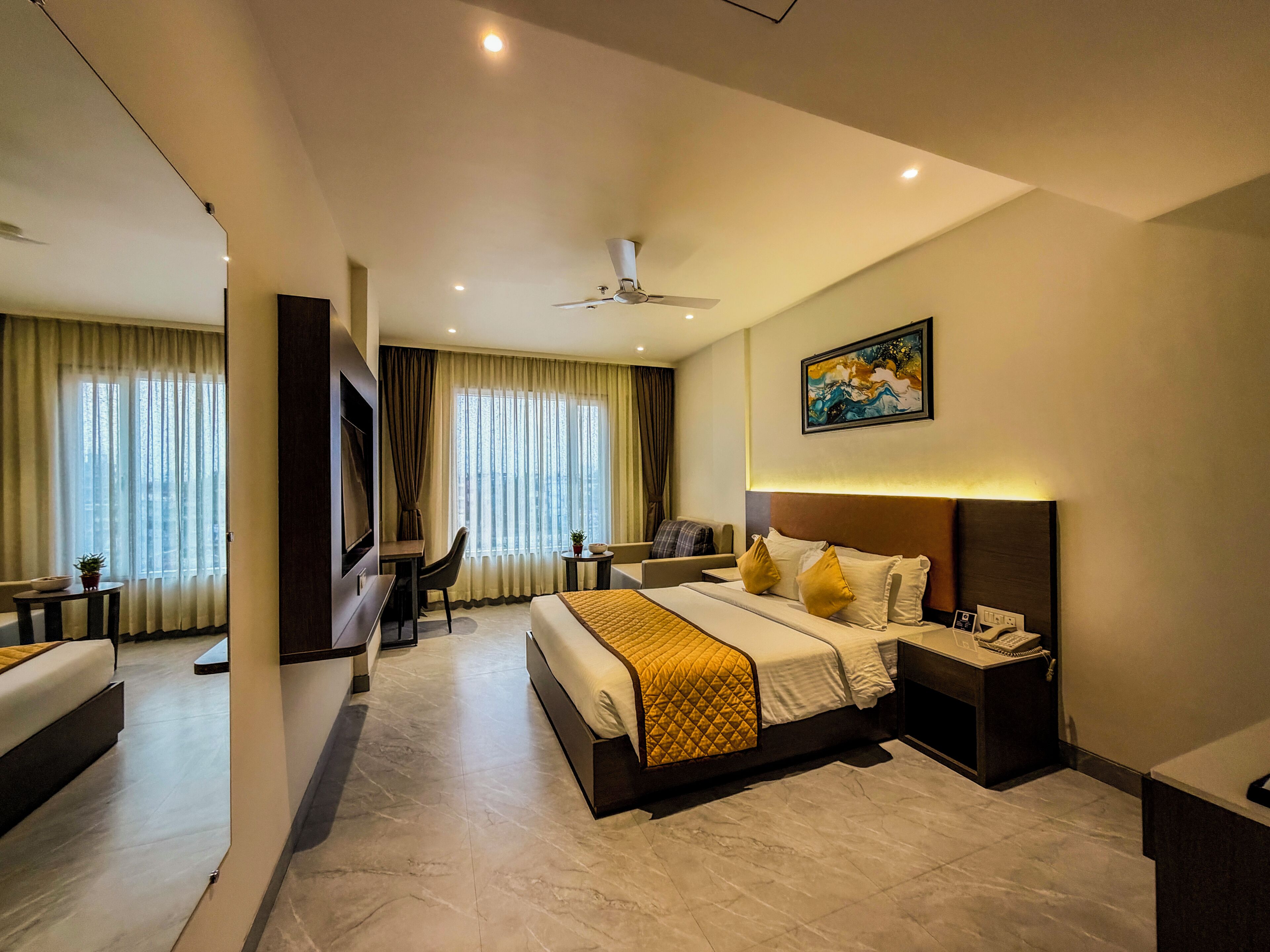 A hotel room with a bed, bedside table, chair, desk, and a ceiling fan.